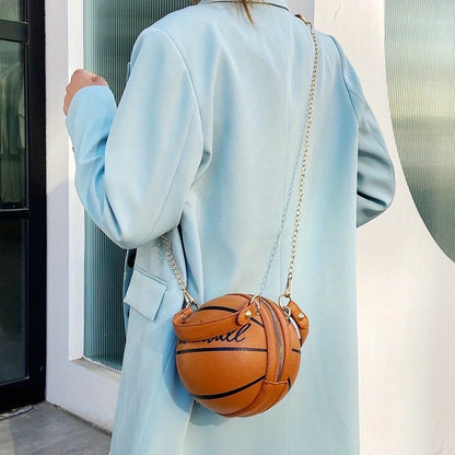 Person wearing a light blue coat holding a small orange handbag shaped like a basketball.