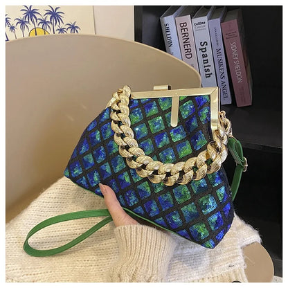 Blue checkered handbag with gold chain strap held by a person, with books in the background.