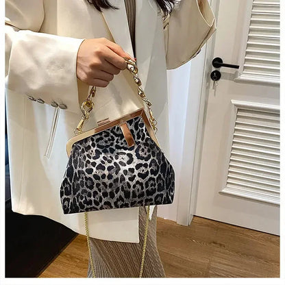 Person holding a Carauana_UNIU_Leopard_Clutch with a gold chain strap indoors.