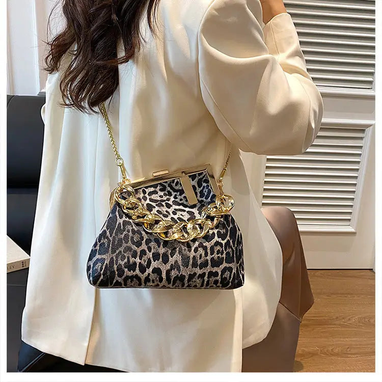 Person wearing a white coat holding a leopard print handbag with gold chain handle.