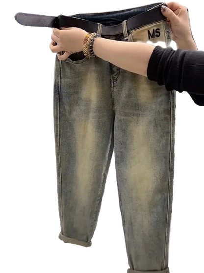 Person holding up a pair of loose-fitting jeans with a belt, showing the size difference.