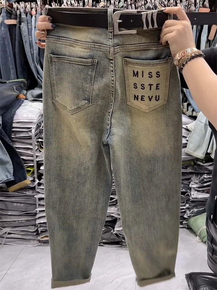 Person holding up a pair of distressed jeans with 'MISS STE NEVU' branding in a store setting.