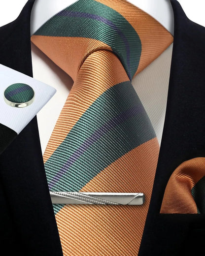 Orange and green striped tie with a tie clip on a white shirt against a black jacket background.