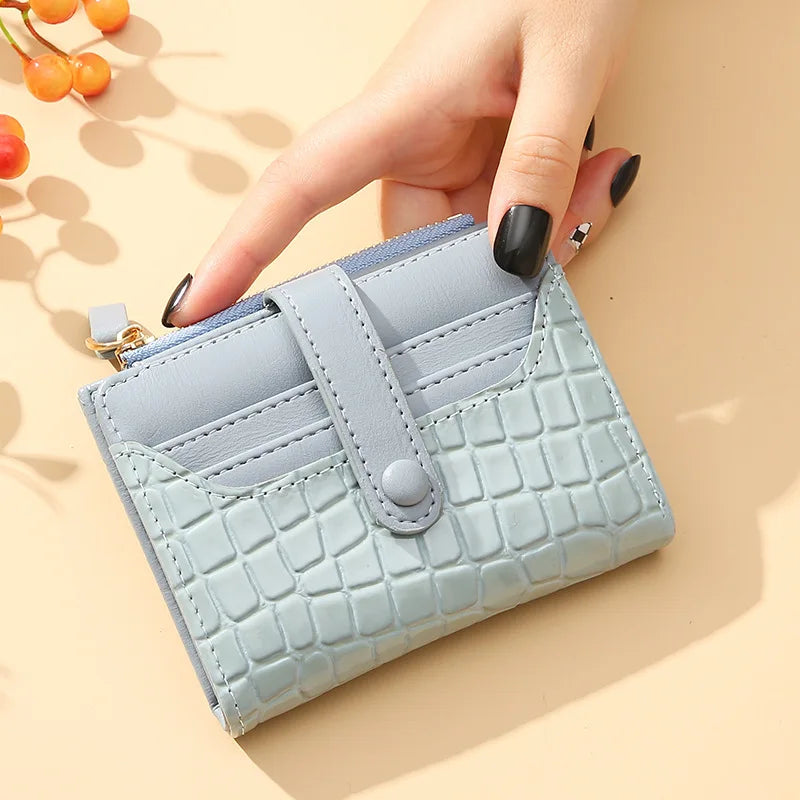 Light blue textured wallet held by a hand on a beige background