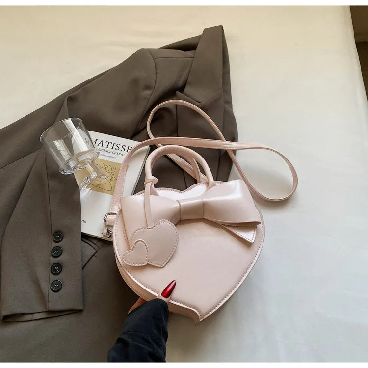 Pink carauana-lovely-shoulder-bag-heartwith a bow and heart design on a surface.